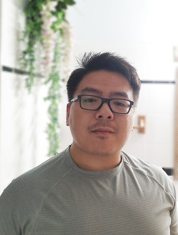 Image of David Pham. Asian guy with short hair wearing black glasses wearing workout clothing in a white room with a plant in the background.